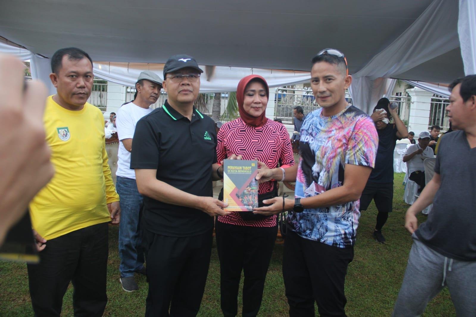 Gubernur Bengkulu, Rohidin Mersyah didampingi anggota DPR-RI dapil Bengkulu, Dewi Coryati (tengah) menyerahkan sebuah buku tentang Festival Tabut kepada Menparekraf Sandiaga Salahuddin Uno.(Foto/Ist)