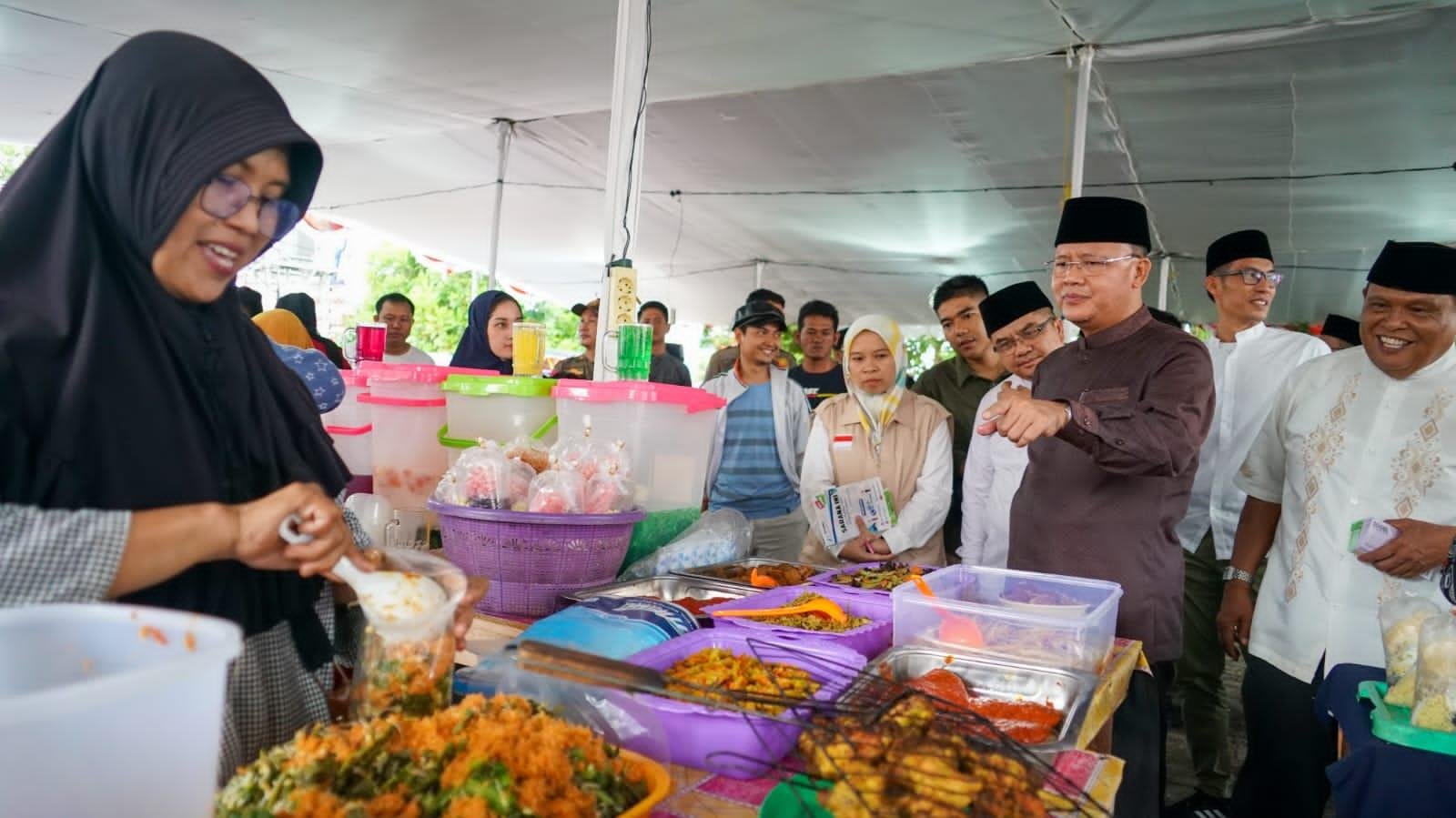 Gubernur Bengkulu, Rohidin Mersyah tengah berdialog dengan salah seorang pedagang lauk pauk kebutuhan berbuka puasa usai membuka secara resmi Kampung Ramadan 1444 Hijriyah.(Foto/Ist)