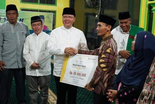 Gubernur Bengkulu, Rohidin Mersyah disaksikan Bupati Mukomuko, Sapuan (kedua dari kiri) menyerahkan bantuan masjid kepada salah seorang pengurus masjid di Kabupaten Mukomuko senilai Rp 50 juta. Bantuan ini disampaikan Gubernur Rohidin dalam lawatan Safari Ramadan ke Kabupaten Mukomuko awal pekan ini.(Foto/Ist)