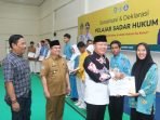 Gubernur Bengkulu, Rohidin Mersyah menyerahkan piagam kepada salah satu siswa SMA Kota Bengkulu, sebagai peserta sosialisasi pelajar sadar hukum.(Foto/Ist)
