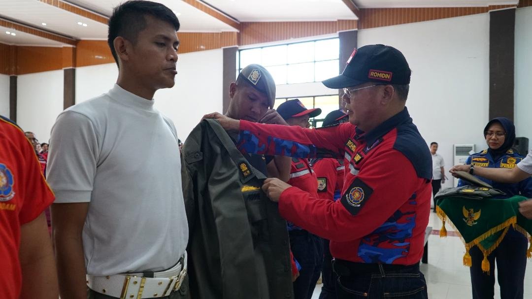 Seragam Baru Satpol PP Gubernur Bengkulu, Rohidin Mersyah memakaikan baju seragam baru kepada salah seorang anggota Satpol PP Pemprov Bengkulu pada acara Bintek dan pengkukuhan rekawan kebakaran Kota Bengkulu.(Foto/Ist)
