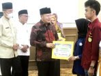 Gubernur Bengkulu, Rohidin Mersyah disaksikan Sekdaprov Bengkulu, Isnan Fajri dan Kepala Diknas Bengkulu, Saidirman menyerahkan bantuan beasiswa berprestasi dari Pemprov Bengkulu kepada mahasiswa penerima.(Foto/Ist)