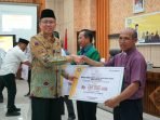 Serahkan Bantuan Dana Hibah Sekdaprov Bengkulu, Isnan Fajri menyerahkan bantuan danah hibah Pemprov Bengkulu kepada sejumlah penerima seusai melauching sistem sistem informasi laporan hibah.(Foto/Ist)