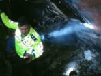 Seorang anggota polisi tengah membantu bus alami kecelakaan masuk jurang dan terbakar di kawasan hutan TNBBS, Kabupaten Pesisir Barat, Provinsi Lampung, Rabu 11 Desenber 2024.(Foto-Istimewa)