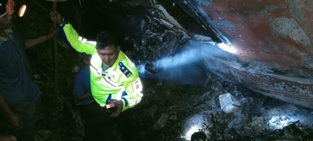 Seorang anggota polisi tengah membantu bus alami kecelakaan masuk jurang dan terbakar di kawasan hutan TNBBS, Kabupaten Pesisir Barat, Provinsi Lampung, Rabu 11 Desenber 2024.(Foto-Istimewa)