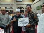 Reward dari Gubernur Bengkulu pengurus masjid Gubernur Bengkulu, Helmi Hasan disaksikan Rektor Universitas Negeri Islam Fatmawati Soekarno Bengkulu, Zulkarnain Dali (kanan) memberikan reward kepada belasan mustahik yang dinilai disiplin berinfaq.(Foto/Ist)